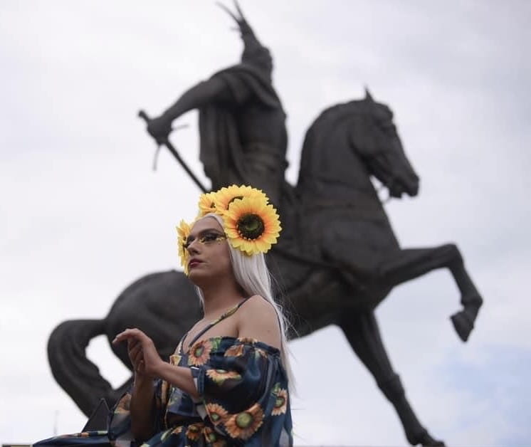 Adelina Rose, za razliku od toga, nikada nije planirao/la da se skrasi u Prištini. Uprkos početnim sumnjama, ono što je trebalo da bude kratkotrajni boravak zbog snimanja kratkog filma “Bini” na Kosovu, za nju/ega se pretvorilo u godine uživanja u gradu kao komična kraljica, talentovani/a glumac/ica i izvođač/ica. U Prištini je upoznao/la našu uvaženu kraljicu svih kraljica, Adelinu Ismaili — istaknutu kosovsku pevačicu iz 1990-ih, pokretačicu raznih tabu tema u pop muzici — koja je postala njena/gova “drag majka”. Danas je pravo zadovoljstvo svedočiti njenom/govom vladanju scenom. 
